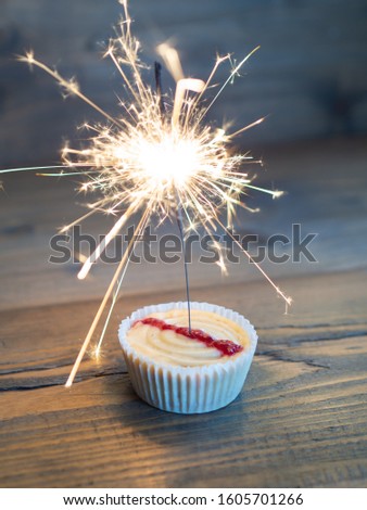 Beautiful cupcake with a lighted sparkler on a wooden background
