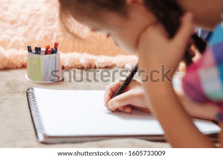 cute little girl drawing pictures while lying on bed