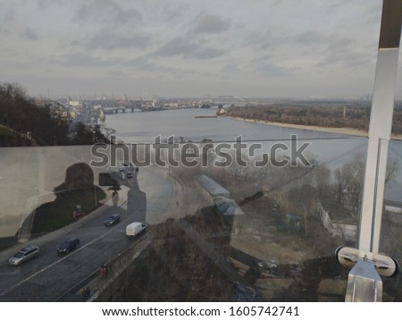 aerial view of the city of Kiev with Dnieper river, cloudy weather, Podilsky bridge visible, reflection of photographer  with camera,  raised hand and spread fingers