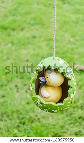 Artificial baby chick in egg hanging in the garden