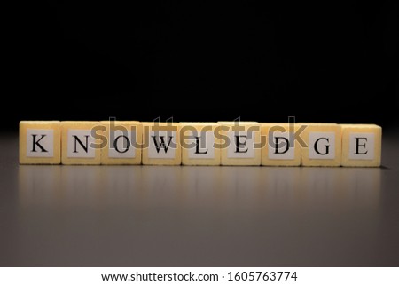 The word KNOWLEDGE written on wooden cubes isolated on a black background...