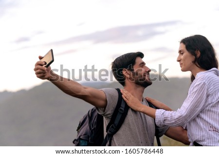 Couple taking Selfie Photo with Smart Phone Hiking on Mountain. Caucasian Woman and Man Hikers Smiling Happy taking a selfie in the Nature. Hiking Couple Concept.
