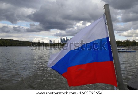 Russian flag on the cloudy sky background. Moscow river. Moscow. Russia