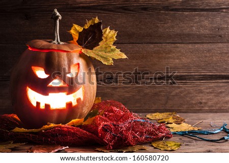 jack-o-lantern with leaves on wooden background