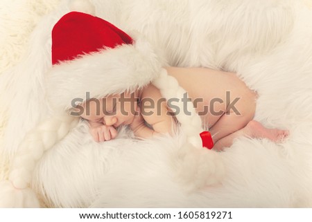 cute newborn girl in christmas cap sleeping on white fur