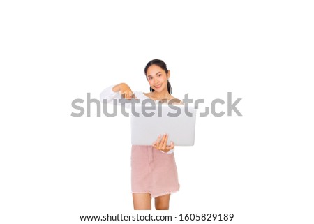 The beautiful Asian girl is holding and pointing to a new laptop on her hands.