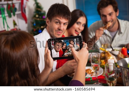 Young friends taking picture with digital tablet on Christmas eve. 