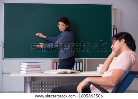 Old female teacher and male student in the classroom