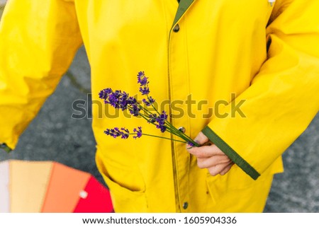 girl in a yellow raincoat holds lavender stalks in her hands. autumn