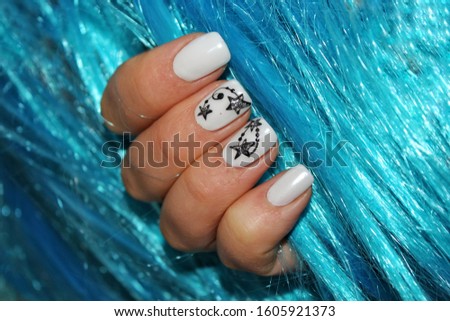 White mother of pearl manicure with black stars on blue background. Stylish fashionable woman's manicure. Nail polish. Artistic manicure. Modern style. Winter manicure.