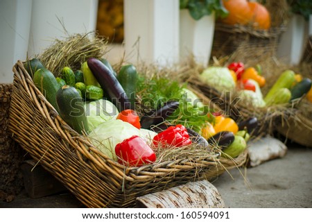 Zucchini, peppers, eggplants and cabbages in basket with straw on city market