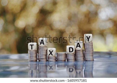 Close up stack of coin and wooden text block on table, saving and manage money to success business technology, tax day concept, vintage tone