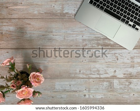 Image of laptop, light orange roses, on wooden table background. Concept of business copy space.