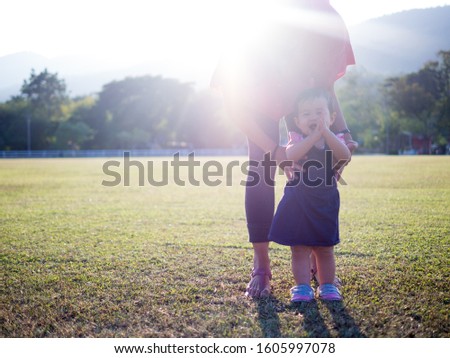 Silhouette of mother help her baby walk the first step and baby clap her hands happily.(selective focus)