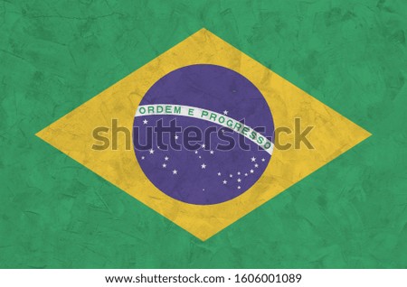 Brazil flag depicted in bright paint colors on old relief plastering wall. Textured banner on rough background