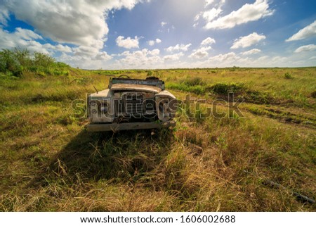 abandoned car under puffy blue skies at Chuping Estate in Perlis