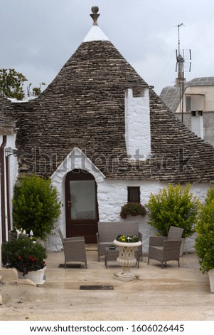 Traditional Trulli house in cozy little countryard  with a lots of greenery and wet pavement after rain