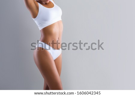 Cropped of afro woman showing her beautiful body over grey studio background with empty space, slimming concept