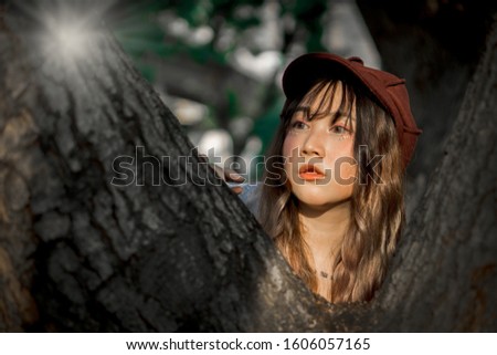 Fashion portrait of young pretty light skin woman with tree at outdoor park.