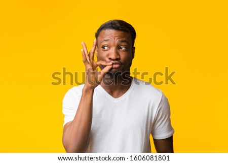 Keep Secret. African American Guy Gesturing Zip Your Lip Standing Over Yellow Background. Studio Shot