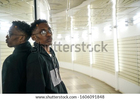 Goodlooking sad young african american man standing in hallway.  portrait of handsome black male standing in modern hall . passage in long perspective. looking donw.