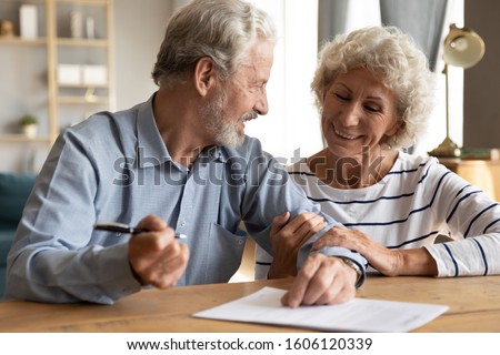 70s couple sit at table indoor discuss agreement term and condition feels satisfied make financial deal ready to sign contract, bequeath savings and property to their children or grandchildren concept