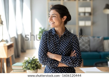 Happy satisfied young indian woman student teacher freelancer look away dream about good future vision, smiling pretty girl professional stand arms crossed at home hope for new opportunities concept Royalty-Free Stock Photo #1606120444