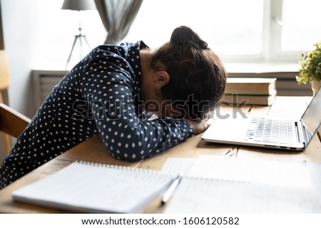 Tired teen girl indian university student fall asleep exhausted after difficult learn exam test, deprived lazy young woman sleeping sit at desk feel fatigue having nap dozing bored of study concept
