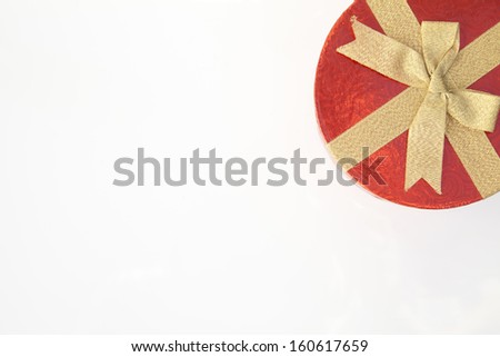 a red gift box with gold ribbon bow , from above at the top right corner