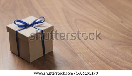 eco friendly paper gift box with blue ribbon on walnut table with copy space