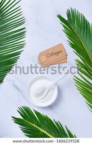 Collagen powder on a trendy marble background with green palm leaves. Natural beauty and health supplement, wellness skincare anti-aging concept. Top view, flat lay, copy space