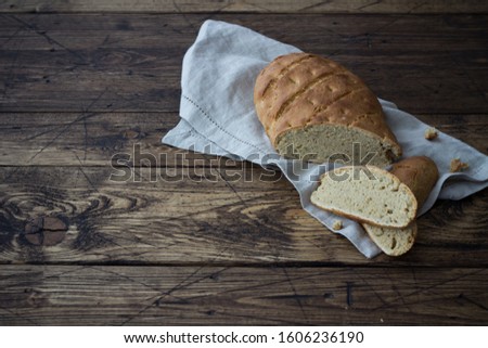 Homemade rustic bread on a textile napkin and aged dark wooden background, close up, free space