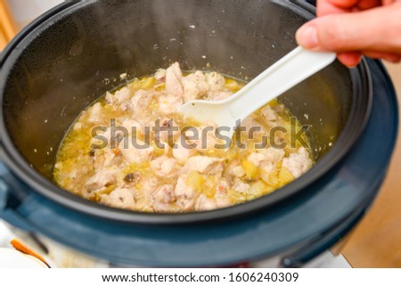 Woman stirs the stew with a white spoon in a slow cooker.