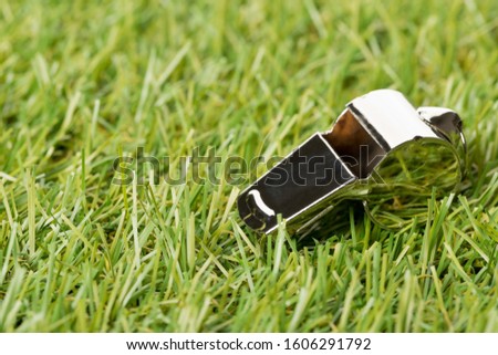 Soccer sports silver chrome whistle on grass background - penalty, foul or sports concept, selective focus
