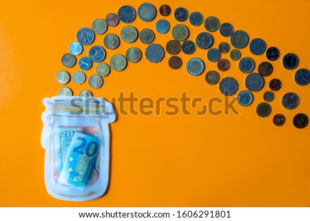 Coins in different currency flowing in to a piggy bank with copy space