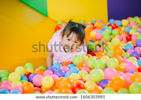 Smiling baby playing in the balls pool. Cute and happy girl. Picture for developmental in children concept.