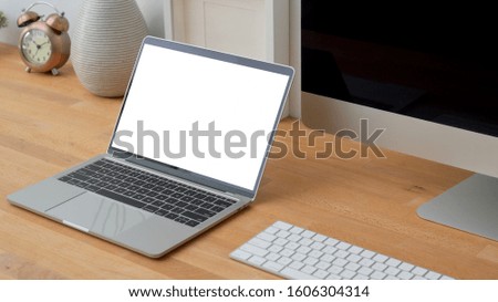 Close up view of modern workspace with blank screen laptop, computer and decoration on wooden desk background