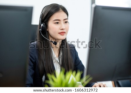 The Asian women call center is working in front of the computer with smiling face.
