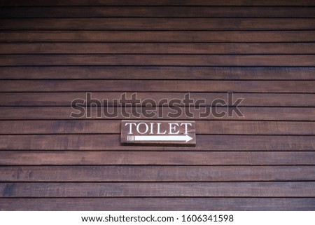 Toilet direction sign on slat plank wall