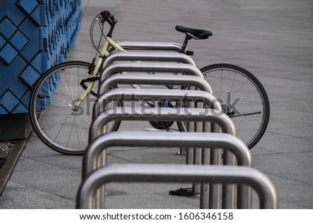 One old bike is fixed to a metal structure for Parking bicycles or scooters, environmental transport in the city. Moving by bike every day. bicycle at street parking outdoors Royalty-Free Stock Photo #1606346158