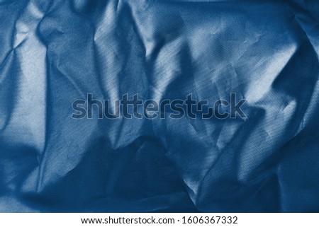 Holographic texture fabric classic blue colors with folds. Holographic color wrinkled crumpled foil. Color of the year 2020.