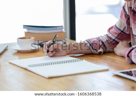 Asian woman writing something in her notebook. business women hand writing something on her paper note.