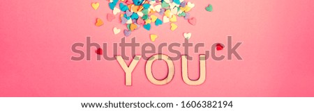 Happy Valentine Day. Beautiful card with colorful hearts candies on pink background. Concept of love. February holiday. Wooden word letters saying you.  Web banner header for website.