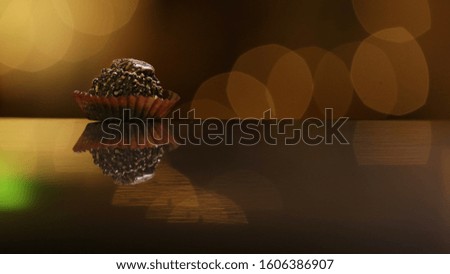 chocolate ball inside a decorative paper. black marble floor reflection. bokeh background. gourmet chocolate. handmade chocolate.