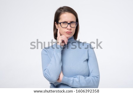 Business caucasian woman in glasses thinking trying to make a decision. Studio shot