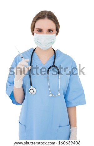 Young female doctor holding an injection while looking into the camera