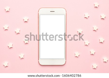 Mobile phone and white sweet star lollipops on a pink background macro view