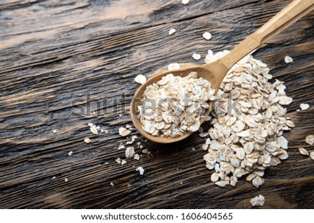 uncooked oatmeal in spoons brown wooden background. place for text

