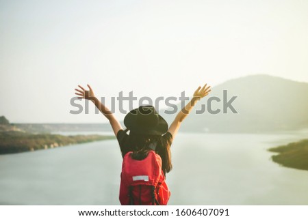 Happy hipster young girl with red backpack raise hands up  in sunset,Traveling alone concept.