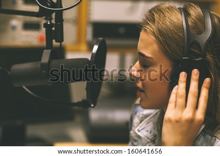 Focused pretty singer recording a song in studio at college